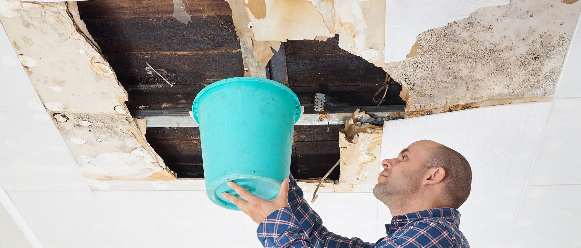 ceiling leaking with man holding bucket